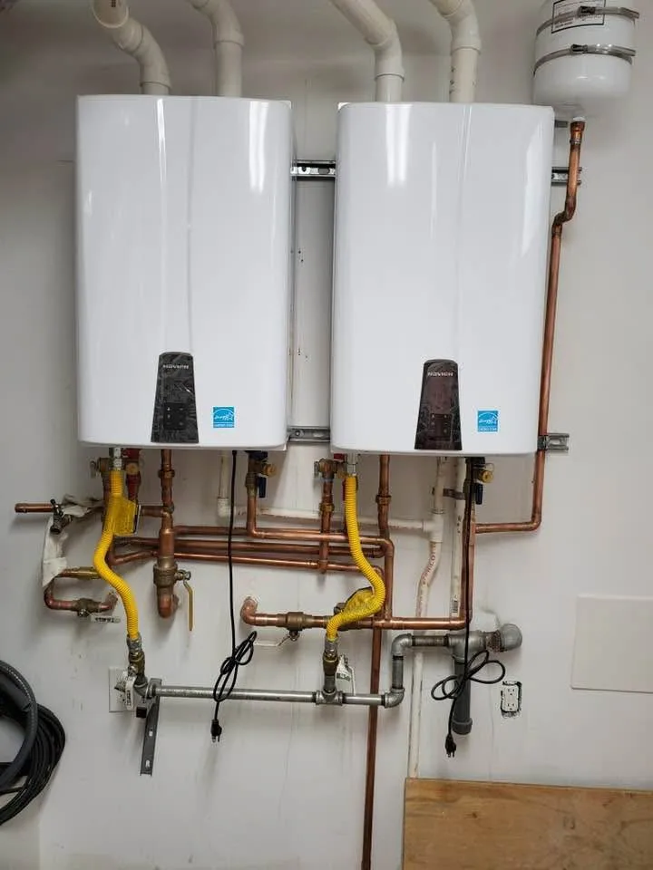 Two tankless water heaters installed side by side with copper and gas piping